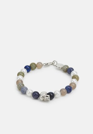 Bracelet avec perles rondes alternées en bleu, vert, beige, blanc nacré, et un pendentif tête de mort en argent central avec fermeture à clip.
