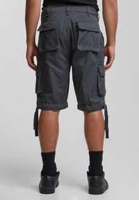 Shorts cargo en tissu gris foncé avec une coupe relaxée, dotés de plusieurs poches latérales et arrière, de revers roulés et de attaches latérales pour ajustement.