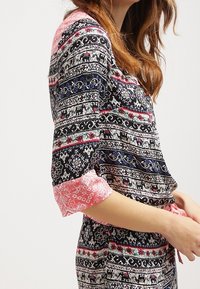 Robe multicolore sur fond noir présentant des motifs complexes, des manches roses et des motifs animaliers. Tissu léger avec une coupe décontractée.