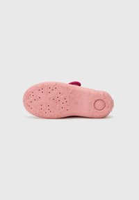 Pink rubber shoe sole with texture featuring flower-like patterns and drainage holes, curved shape, and a round knob at the heel.