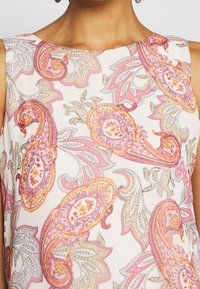 Ärmløs top med hvid bund og intrikate pink og orange paisley mønstre samt blomsterdetaljer, lavet af letvægtsstof.