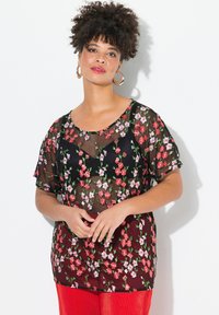 Top in rete nera con fiori ricamati rossi e rosa, maniche corte e scollatura rotonda, sovrapposto a una base nera solida.