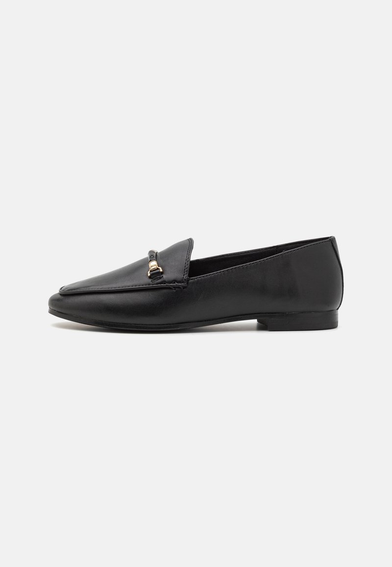Mocassins en cuir noir avec un bout pointu et un petit accent en métal doré sur le dessus. Semelle plate et design élégant.