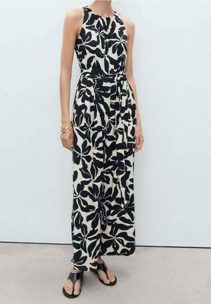 Jumpsuit à motifs floraux noir et blanc avec un design sans manches et col montant, taille cintrée et silhouette à jambes larges ; assorti à des sandales plates.
