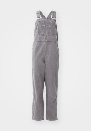 Bretelle in denim grigio con spalline regolabili, una tasca frontale e una vestibilità rilassata. Presenta gambe a taglio dritto e un colore uniforme.