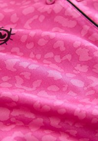 Țesătură cu imprimeu leopard roz, cu textură moale. Prezintă un mic desen cu ochi negri și nasturi. Predominant nuanțe de roz deschis și închis.