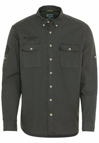 Chemise à manches longues gris foncé avec un col structuré, deux poches poitrine, un texte brodé et des accents de boutons. Texture lisse.