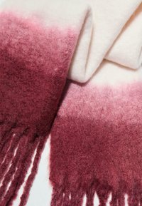 Scarf caldo in maglia con design ombre. I colori passano da un bordeaux intenso a un rosa chiaro, rifinito con bordi frangiati. Morbido al tatto.