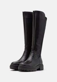 Bottes noires mi-hautes en cuir texturé, dotées d'une semelle épaisse et d'accents lisses, conçues avec une tige ajustée.