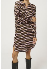 Langärmliges Kleid mit geometrischem Muster in Pink, Braun und Schwarz, mit V-Ausschnitt und seitlichen Schlitzen für Bewegungsfreiheit.
