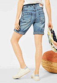 Szorty dżinsowe w niebiesko-białe paski, z podwiniętymi mankietami, dwiema tylnymi kieszeniami oraz metką na pasie. Casualowe białe trampki.