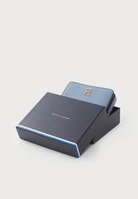 Blue leather wallet with gold hardware featuring the logo. Presented in a navy box with a white and red accent stripe.