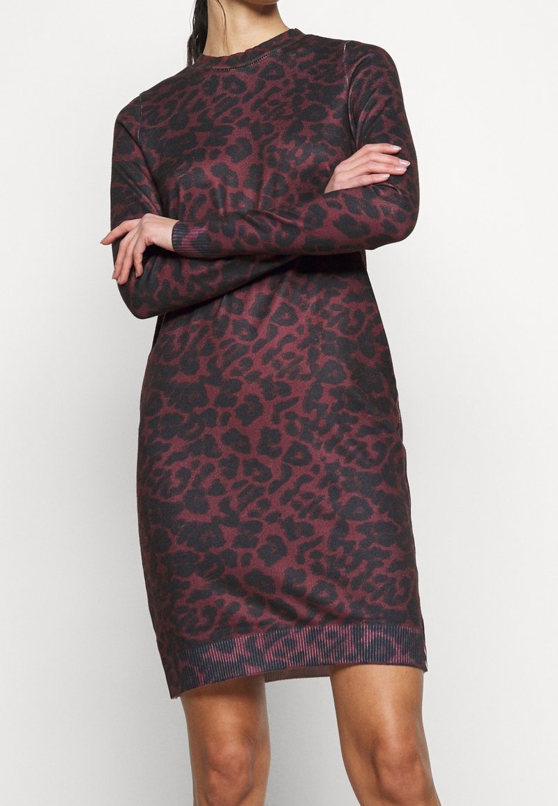 Leopardmönstrad tröjdress i mörkröd och svart. Långa ärmar, ribbad mudd och fåll. Mjuk stickad tyg med lös passform.