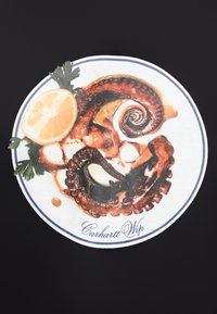 Κυκλικό γραφικό που απεικονίζει ένα μαγειρεμένο χταπόδι με λεμόνι και μαϊντανό, σε λευκό φόντο με μπλε περίγραμμα και κείμενο «Carhartt WIP» από κάτω.