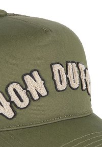 Gorra verde oliva con texto bordado "NON DUTY" en crema y negro, que presenta un diseño estructurado y una tela texturizada.