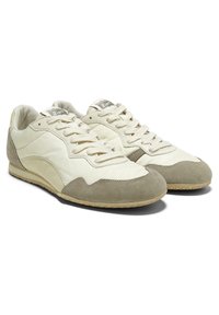 Lys beige sneakers med et glat læderoverdel og ruskindsdetaljer. Rund tå, snørebåndsdesign og struktureret gummisål. Diskret logo på tungen.