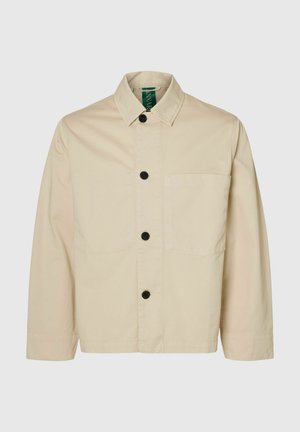 Veste beige clair dotée d'un col, de boutons sur le devant, d'une poche poitrine unique et de manches longues avec une coupe décontractée. Tissu à la texture douce.