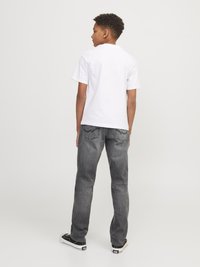 White short-sleeve t-shirt paired with gray denim jeans, featuring a straight cut, five pockets, and black skate shoes.