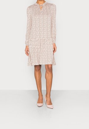 Robe à manches longues, longueur genoux, imprimé floral petit et dispersé, col goutte d'eau noué, associée à des chaussures à talons hauts rose clair.