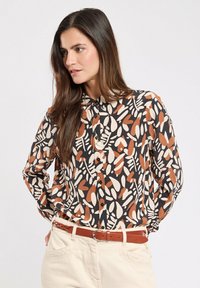 Long-sleeve button-up shirt featuring a black base with abstract leaf patterns in orange, cream, and light brown. Soft fabric with a collared neckline.
