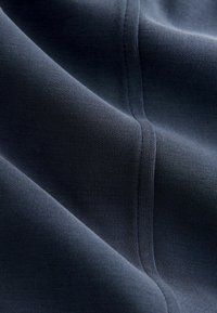 Granatowa tkanina o gładkiej fakturze, z subtelnym prążkowaniem i detalami szwów. Materiał wydaje się elastyczny i lekki.