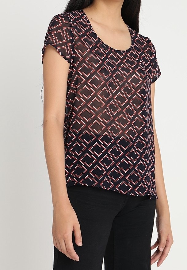 Blouse transparente à manches courtes avec un motif géométrique en marine foncé, rose et blanc. Encolure arrondie, tissu léger et coupe décontractée.