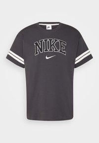 Tmavě šedé bavlněné tričko s velkým vyšitým nápisem „NIKE“ a bílými pruhy na rukávech. Klasický kulatý výstřih.