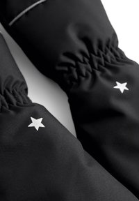 Mustat kangaslämmittimet, joissa on rypistynyt ranneosa ja pieniä valkoisia tähden kuvioita ulkopuolella. Silkkinen rakenne, minimalistinen muotoilu.