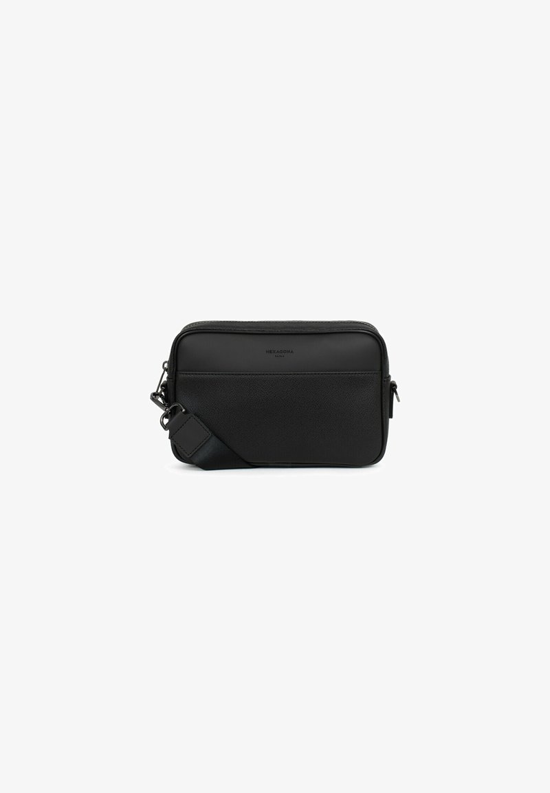 Sac en cuir noir à bandoulière avec finition texturée, fermeture zippée et bandoulière réglable. Présente un design minimaliste et un branding subtil.