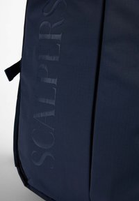 Ciemnogranatowy plecak z subtelnym wytłoczonym pionowym napisem "SCALPERS" na przednim materiale.