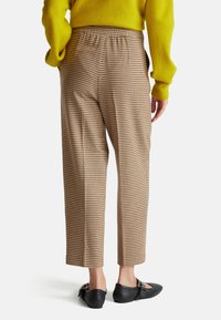 Bruine geruite broek met elastische tailleband, cropped rechte pijpen design, gecombineerd met zwarte ballerina's met decoratieve hardware.
