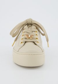 Beige kožené tenisky s texturovanou podrážkou, zaobleným tvarem, zlatými očky a dekorativním detailem motýla na tkaničkách.