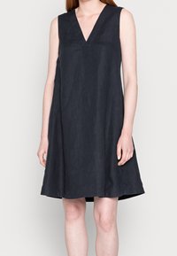 Robe noire sans manches avec un décolleté en V, fabriquée dans un tissu texturé. Silhouette évasée atteignant le mi-cuisse, sans accents supplémentaires.