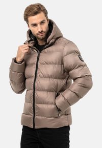 Daunenjacke in Taupe, mit hohem Kragen, Reißverschluss vorne, seitlichen Taschen und gerippten Bündchen. Glattes, glänzendes Material mit horizontaler Steppung.
