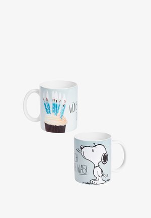 White mugs with birthday design; one shows a cupcake with lit blue candles, the other features Snoopy cartoon and partial German text.