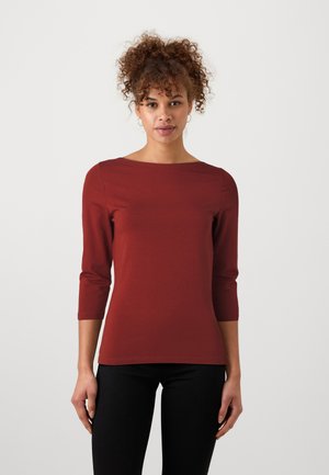 Bordeaux, tettsittende topp med båthals og trekvart ermer. Glatt tekstur, minimalistisk design, kombinert med svarte, smale bukser.