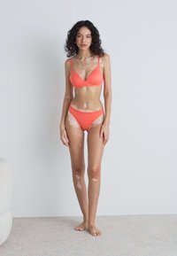 Top și fundiță de bikini corai cu textură netedă și design minimalist. Topul prezintă bretele subțiri, iar fundița are o croială clasică.