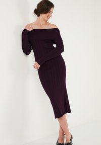 Abito a spalle scoperte in maglia a coste di un profondo viola, design aderente, maniche lunghe, lunghezza a metà polpaccio, texture morbida, con un discreto dettaglio sull'orlo.