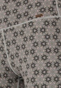 Lichte stretchy stof legging met een geometrisch bloempatroon in tinten van grijs, roze en zwart, met een metalen logo-accent.