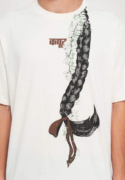 Weißes T-Shirt mit einem grafischen Motiv von schwarzem geflochtenem Haar, ergänzt mit grünen und weißen floralen Akzenten, die mit einem braunen Band gebunden sind, sowie stilisiertem Text.