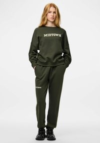 Zielono-oliwkowy komplet bluza i dresy z nadrukiem "MIDTOWN" w kolorze kremowym. Miękka tkanina, luźny krój i boczne kieszenie w spodniach.