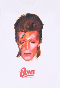 Hvid T-shirt med en grafisk print af et ansigt med røde og blå akcenter, store frisurer og navnet "Bowie" i en fed skrift.