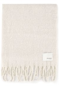 Delikatny, kremowy, pleciony szalik z frędzlami na krawędziach i małą prostokątną metką z napisem "maze EST 2003" w rogu.