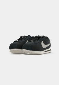 Sorte ruskinds sneakers med en hvid swoosh, med snørelukning og struktureret gummisål. Lavprofil design med polstret krave.