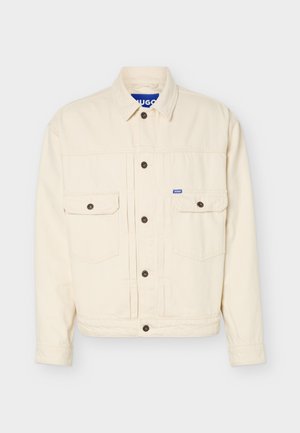 Beige lange mouwen jas met knoopsluiting aan de voorkant, twee borstflapzakken, een kraag en een klein blauw logolabel op de rechterzak.