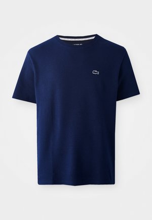 Granatowy T-shirt z okrągłym dekoltem, wykonany z teksturowanej bawełny, z małym białym haftowanym logo na lewej piersi. Krótkie rękawy.