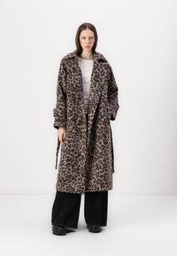 Leopardmønstret frakke lavet af blød stof, med åben front, stor krave, lange ærmer og sidelommer. Båret over en hvid top og sorte bukser.