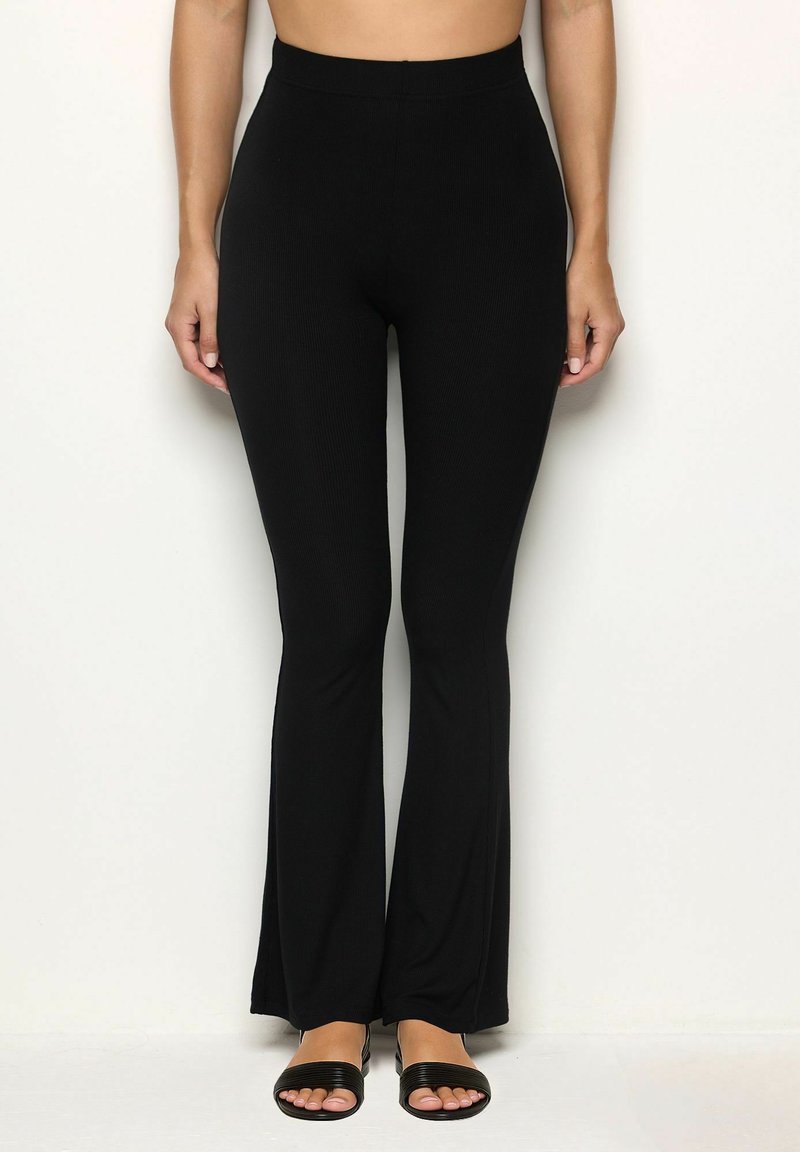 Zwarte geribbelde flare pants met een hoge tailleband, een gladde textuur en een aansluitende silhouet. Gecombineerd met zwarte enkelband sandalen.