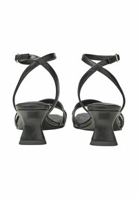 Schwarze Leder-Absatzsandalen mit gekreuzten Riemen, einer runden Zehe und einem ausgestellten Absatz. Glatte Textur und minimale Hardwaredetails.