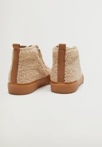 Béžové ankle boots z umělého beránka s hladkým hnědým akcentem vzadu, gumovou podrážkou a bočním zipem.